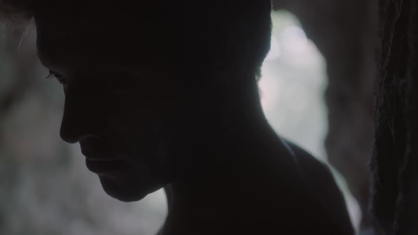 An unmoving, unblinking man stares with his head turned to the left