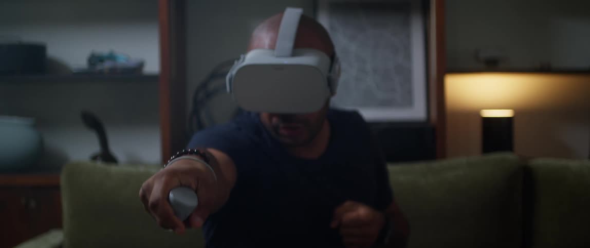 A man plays a virtual reality game while sitting on a sofa indoors