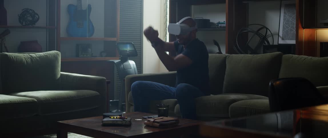 Man sitting on a couch at home wearing a virtual reality headset playing video games at home