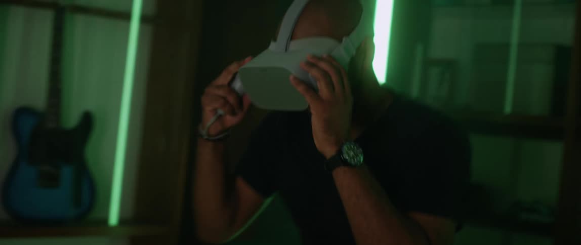 A man makes the motions of serving a tennis ball while playing a game with a virtual reality headset