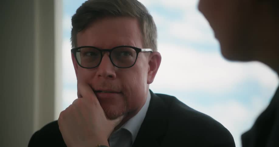 Man wearing casual business attire talking to someone in a meeting at the office