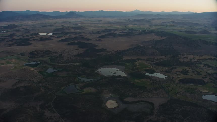 Sunrise aerial of volcanic highlands pocked with lakes and basalt rock in Northern California