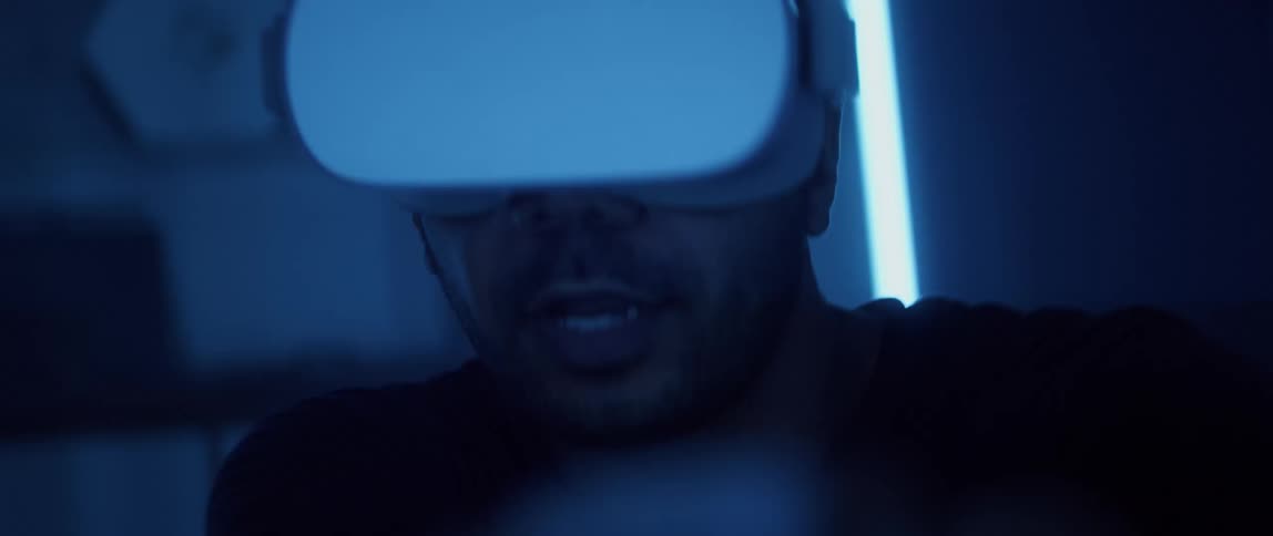 A man wearing a virtual reality headset looks around excitedly while playing a game