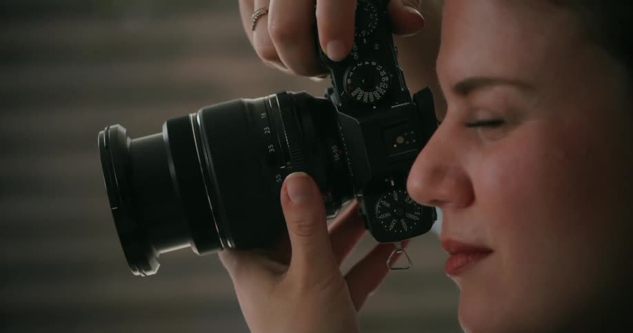 A female photographer carefully holds the camera up to her eye to take a photograph