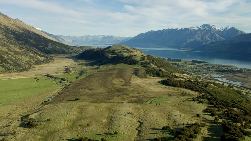 Green hills and mountains in foreground with blue alpine lake in distance