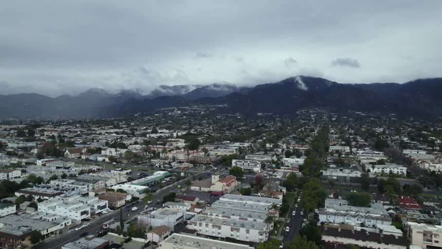 Distant mountains loom over a small city on a cloudy day