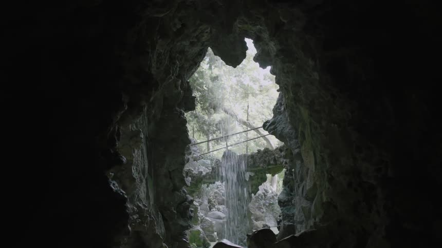 A small waterfall as seen from inside a dark cavernous area