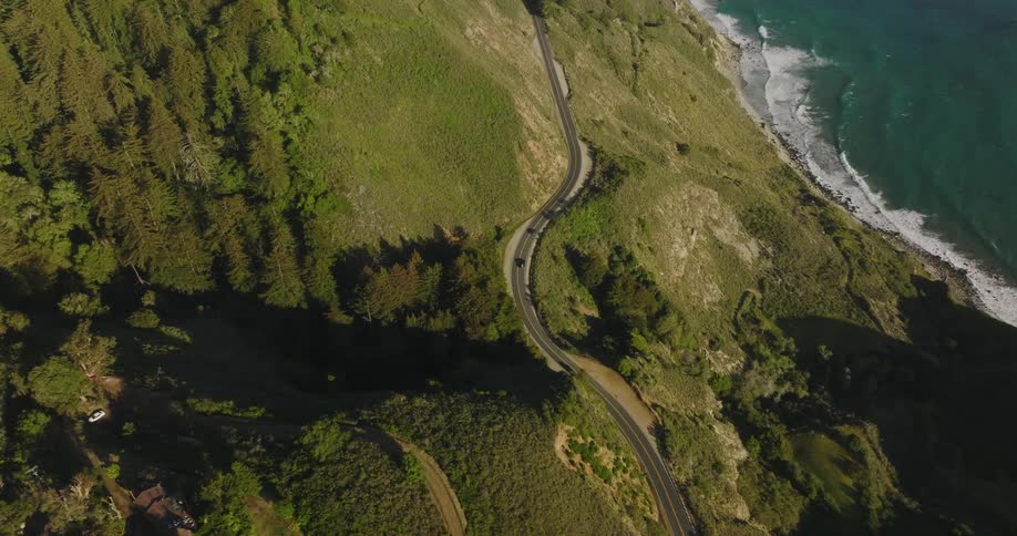 A winding road on a hillside above the coast during the day