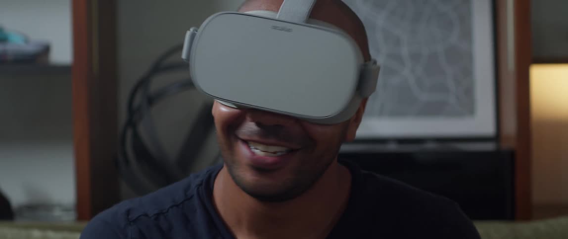 A man wearing a virtual reality headset smiles while talking