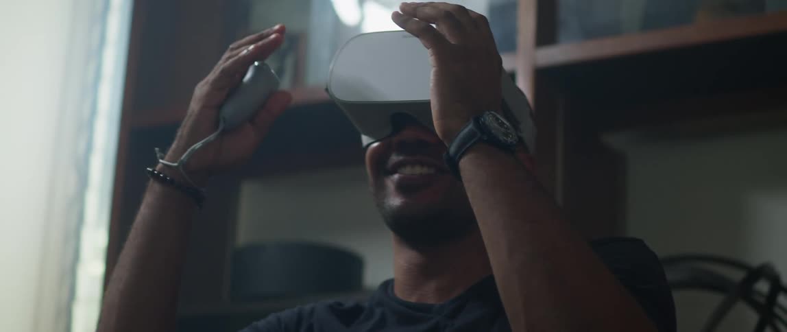 A man laughs while using a virtual reality headset