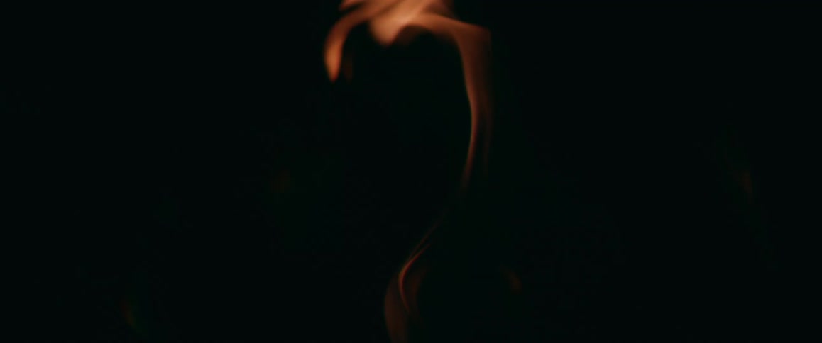 Close up of dim orange flames rising up against a black background