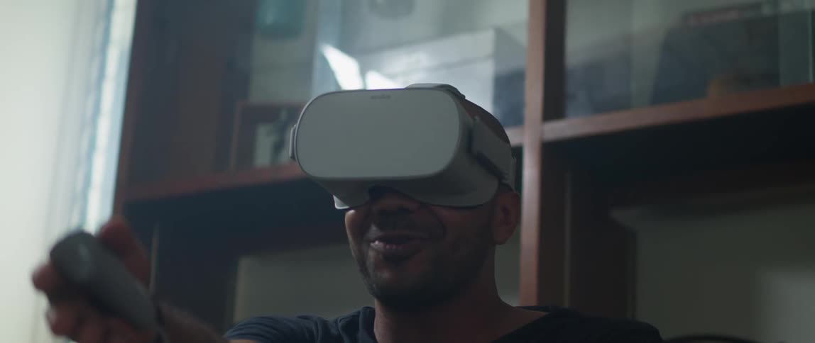 A man makes racket swinging motions with his arms while playing a virtual reality game
