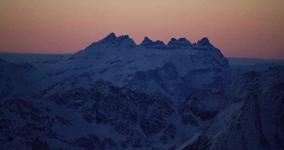 A snow covered mountain range at sunset