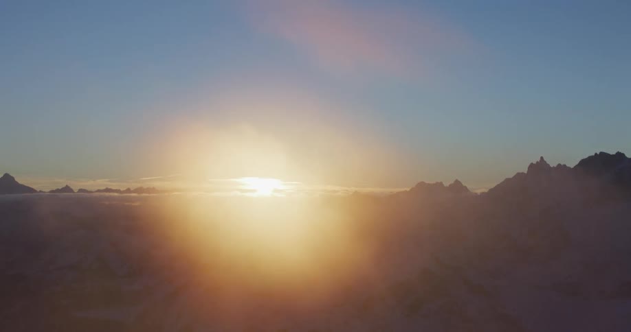 An aerial view of a sunrise over snowy mountains in the wilderness