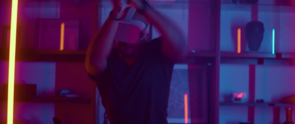 A man is playing a virtual reality game indoors during the night