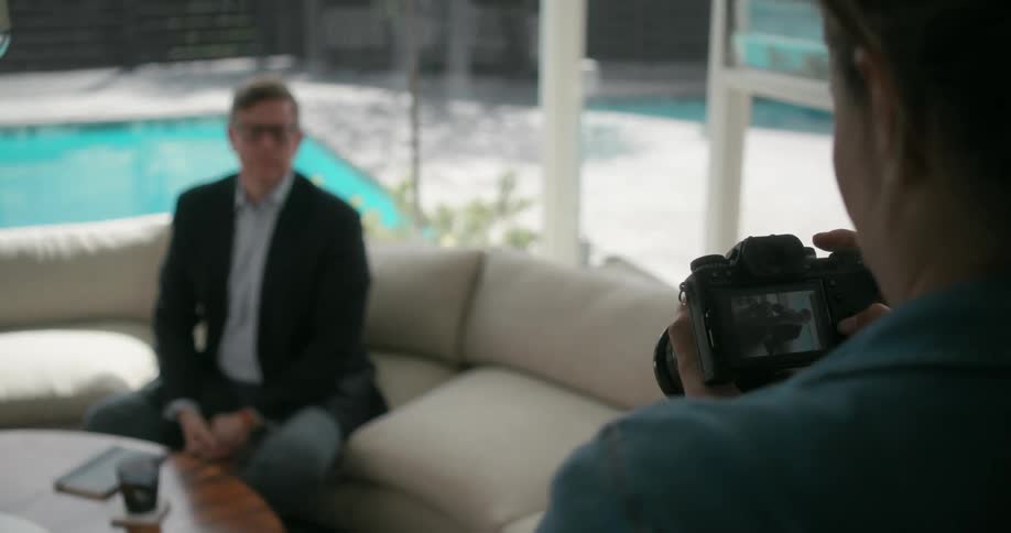 A man is being photographed on the couch