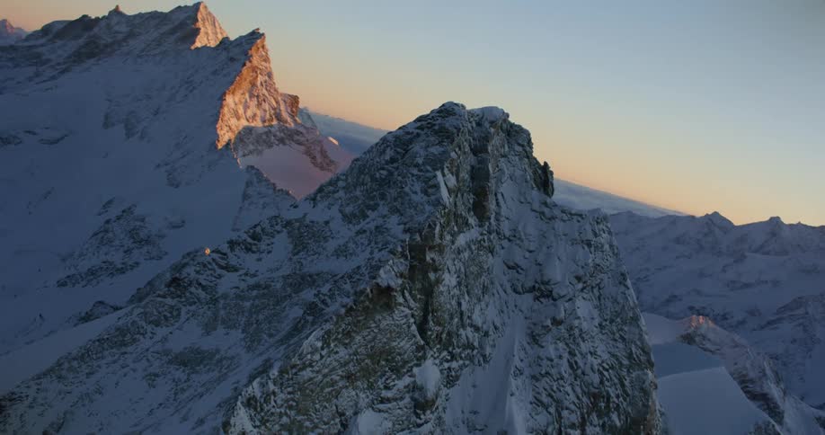 Aerial view of snow covered mountains at sun set is displayed
