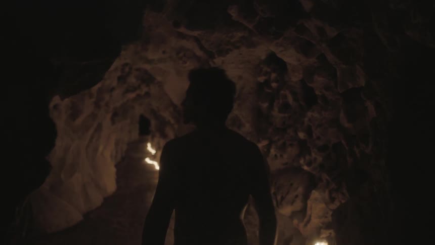 Man walking cautiously through a cave
