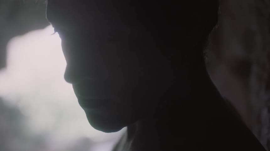 Close-up of a man looking solemn in a cave