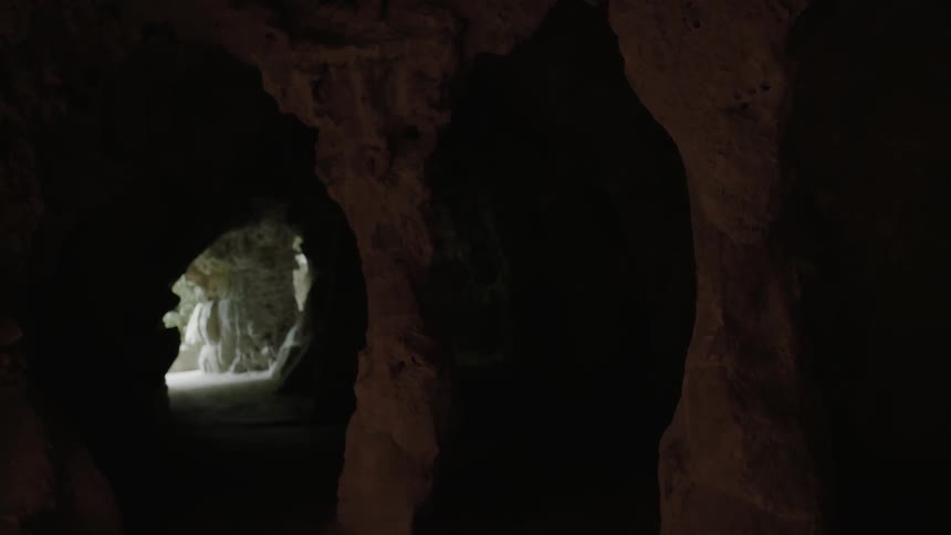 A person is standing in the corner of a very dark cave