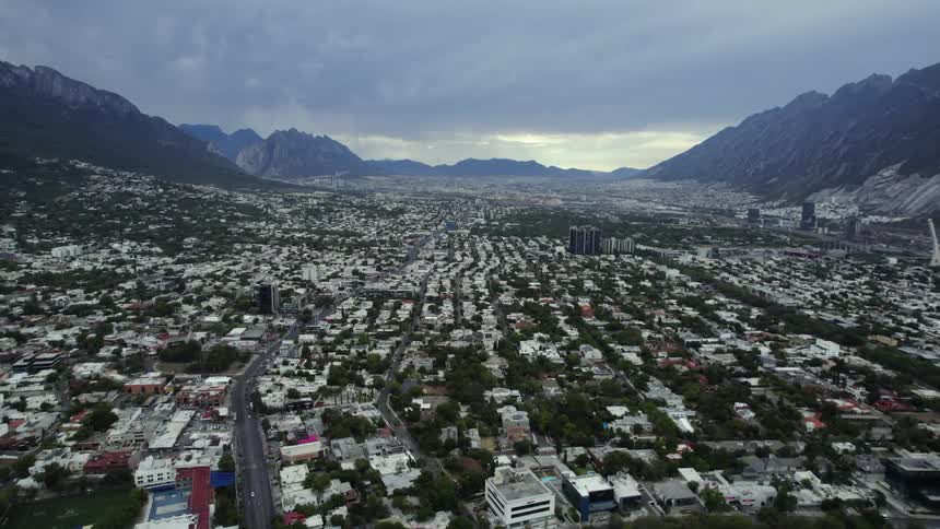 Aerial view of the low buildings on a small city on a valley between mountains at morning