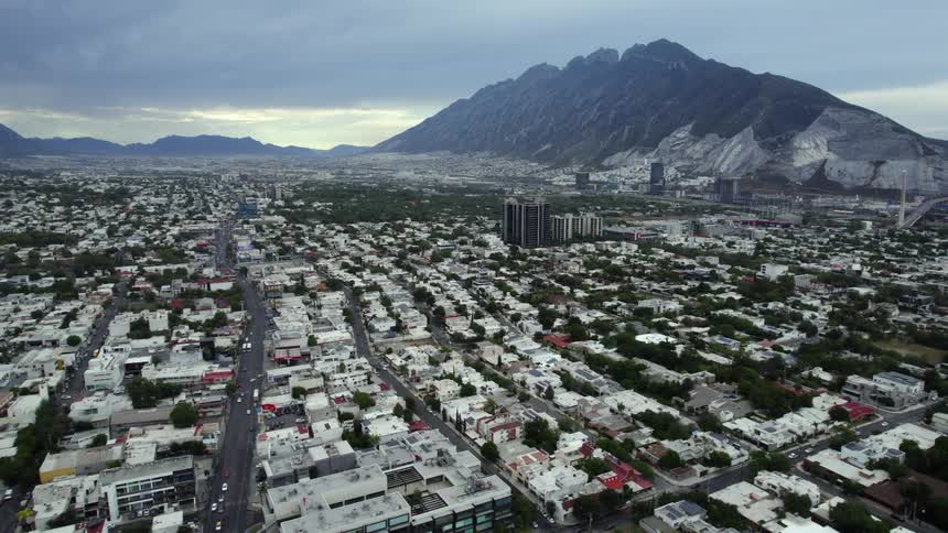 A mountain ridge looms over a city on a cloudy day