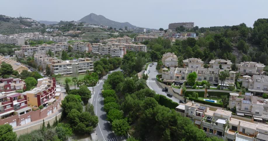 Large homes and colorful apartment buildings fill a neighborhood below mountains