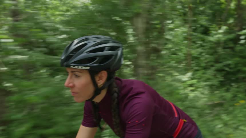A woman wearing a cycling helmet is riding her bicycle through the woods