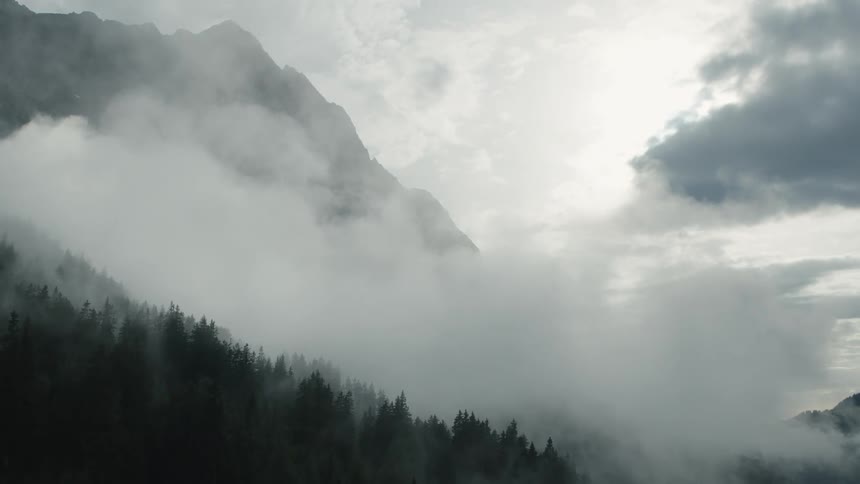 Aerial view of a thick layer of white clouds covering the slopes of a mountain range at morning