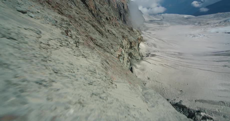 Aerial flyby over the rugged rock slopes of a mountain at daytime