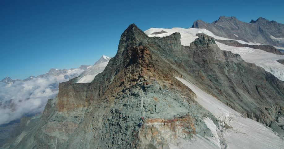 A snow covered mountain ridge with peaks high in a clear blue sky