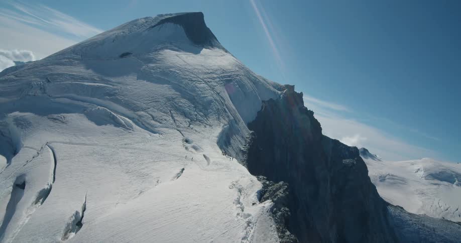 Twisting aerial view of the snow covered slopes of a mountain range at morning