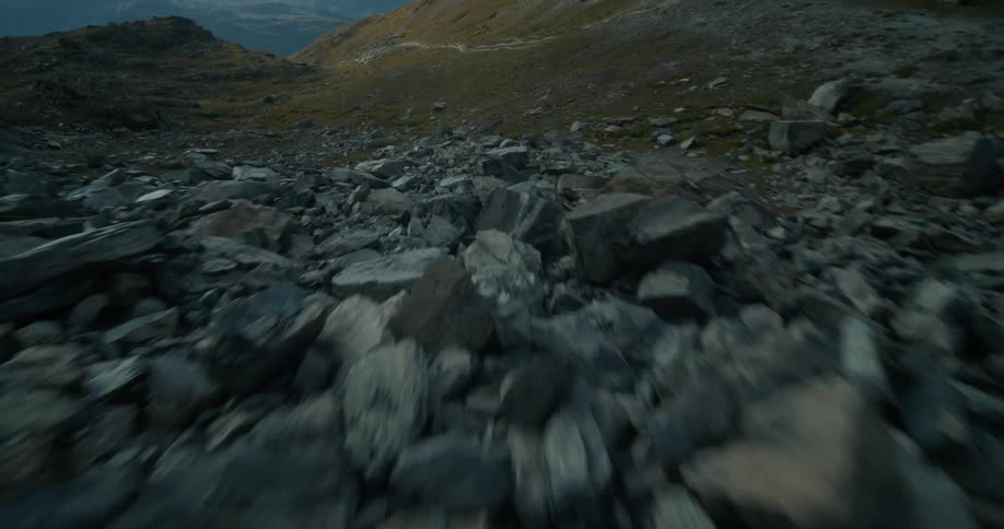 Aerial flyby over the rugged slopes of a mountain covered in rocks at daytime