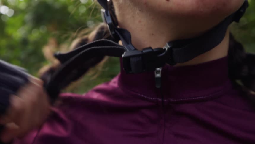 A woman buckles a helmet on her head