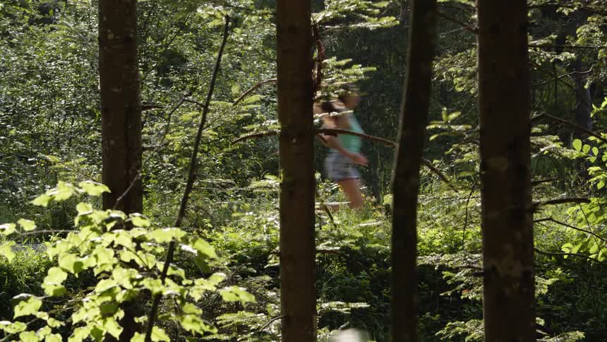 A girl runs through the woods as insects swarm around the trees