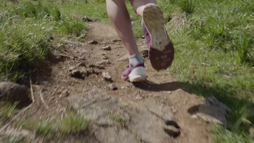 Close up of the legs of a young person jogging on a dirt trail on the counrtyside
