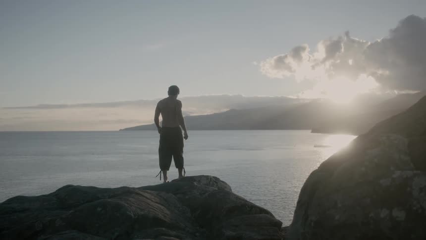 Man walking out on some rocks overlooking the ocean