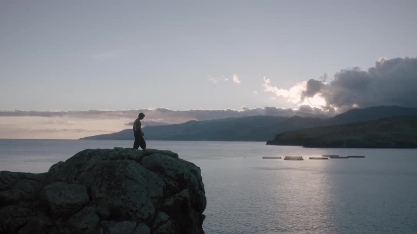 Man walking on rocks high above the beach