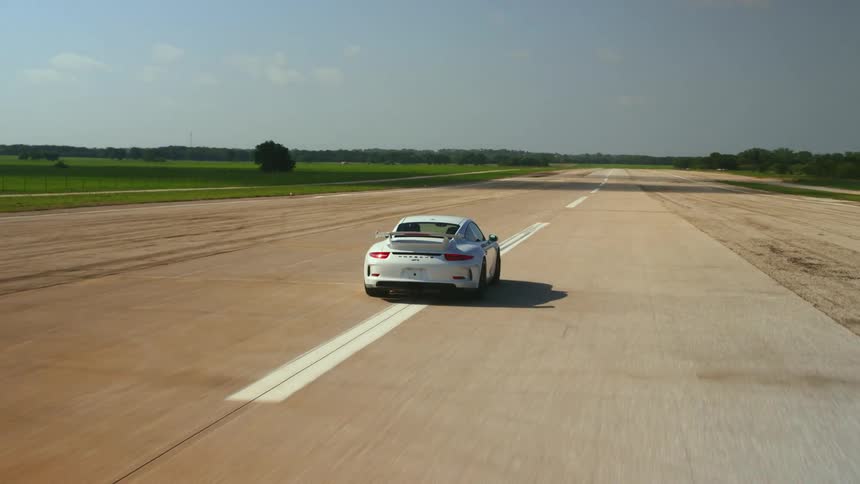 A car driving down a street next to grass fields