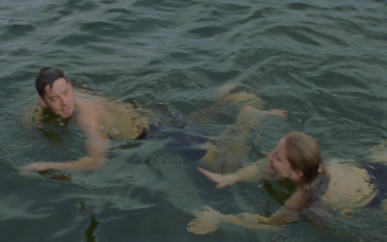 A man looks back at the woman swimming up to him both smiling