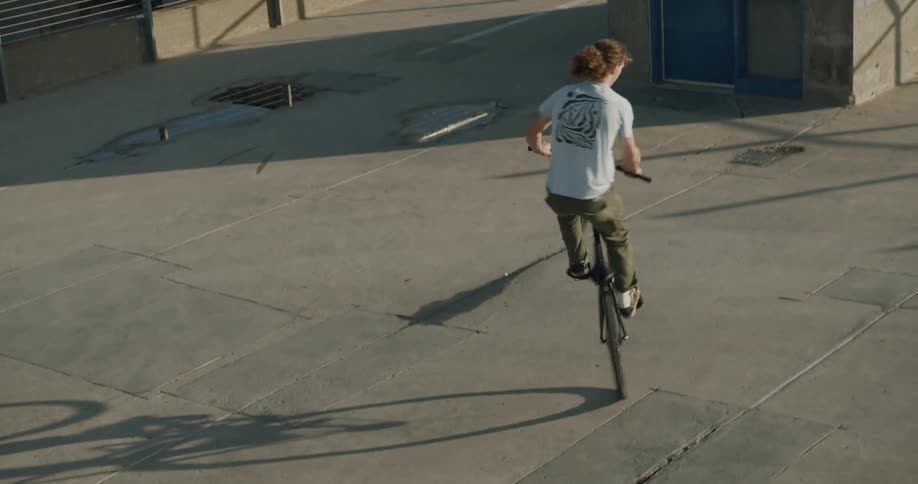 Man riding a bicycle does tricks on the roof of a building at evening