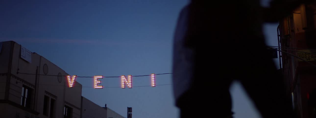 People walk down the street near the iconic venice lights at dawn