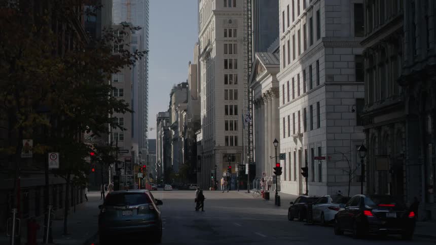 Vehicles wait at a stoplight while pedestrian cross at a city intersection