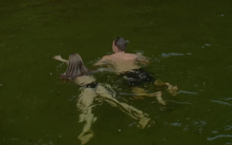 Man and woman are swimming in the water outdoors