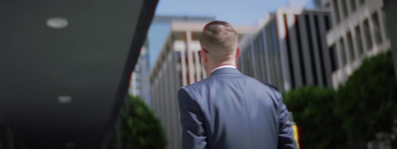 A man wearing a suit walking on a city sidewalk