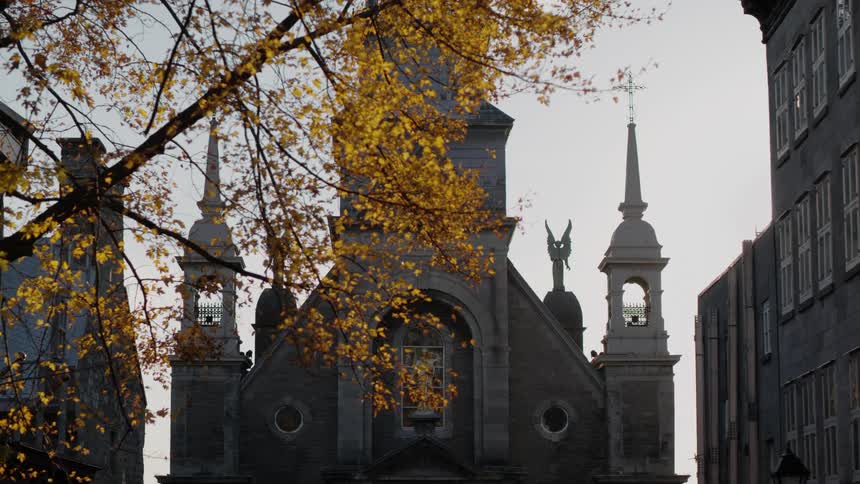 A church behind a building with fall leaves