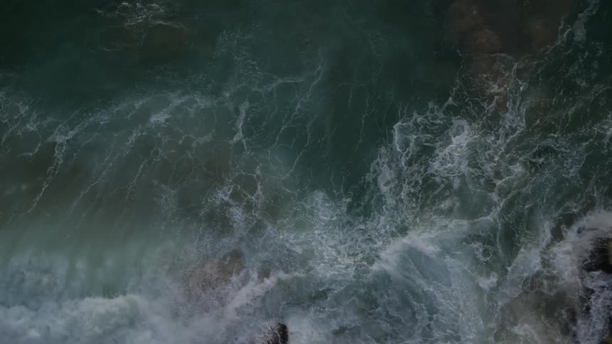 Waves crash and churn against rocks