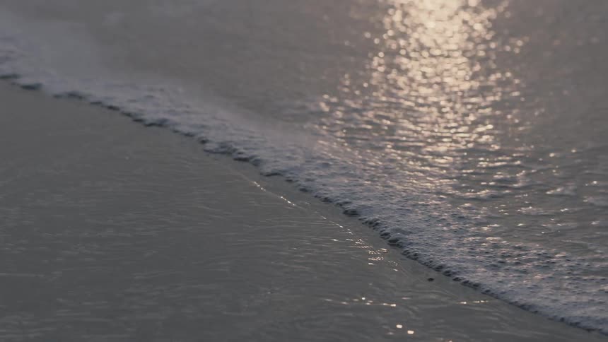 Small waves coming ashore on a beach at sunset