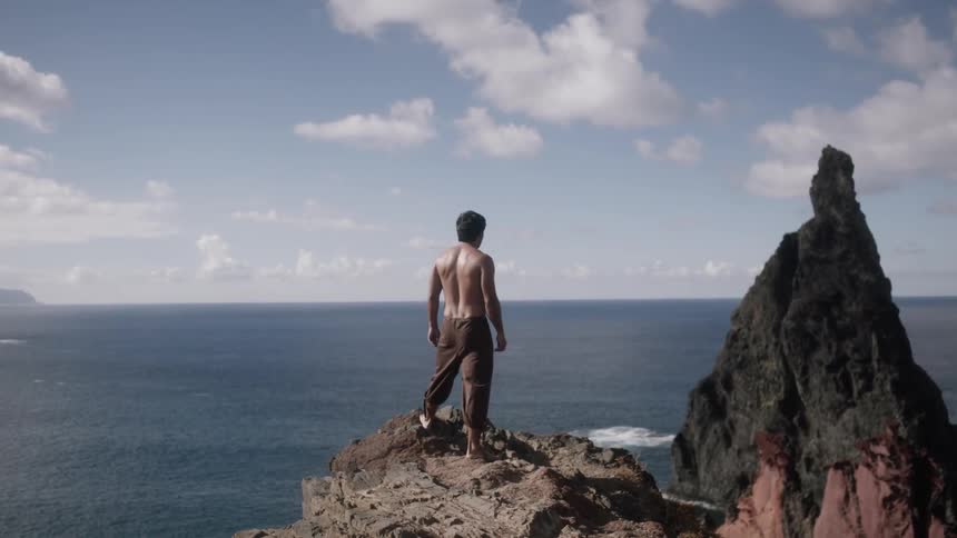Man standing atop a rocky area overlooking the sea