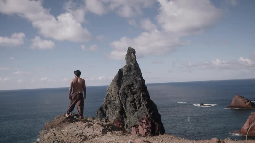 Man standing high atop a beach looking down upon it